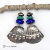 Bold and striking, these handcrafted earrings feature uniquely textured sterling silver accented with natural turquoise and lapis gemstones. They are topped off with Native style oxidized sterling silver beads with a rich, corrugated texture. They have a modern southwestern flair and are perfect for women that love to wear one-of-a-kind artisan handcrafted jewelry. Handmade in the USA by Silver and Earth - a New Mexico True Certified business.