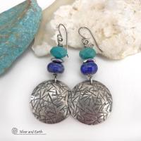 These handcrafted earrings feature sterling silver dangles with a hand stamped texture accented with faceted turquoise and lapis lazuli gemstones. Small hematite gemstones with a faceted finish were added for a touch of natural sparkle and shine. The earrings have a contemporary, modern chic style with a bit of southwestern flair. They'll coordinate beautifully with all wardrobe types - dressed up or down. Handmade in the USA by Silver and Earth Jewelry. 
