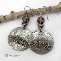 Unique and one-of-a-kind, these handcrafted large sterling silver earrings have a bold edgy vibe. They feature rustic hammered sterling silver accented with natural asteroid jasper stones and stainless steel beads. This type of stone is known for its unique dotted matrix in earth-tone hues of brown, gray and tan. It's also known as chocolate ocean jasper because it's found on the shores of Madagascar where ocean jasper is also found. Bold and striking - they're sure to make a unique statement.