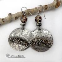 Unique and one-of-a-kind, these handcrafted large sterling silver earrings have a bold edgy vibe. They feature rustic hammered sterling silver accented with natural asteroid jasper stones and stainless steel beads. This type of stone is known for its unique dotted matrix in earth-tone hues of brown, gray and tan. It's also known as chocolate ocean jasper because it's found on the shores of Madagascar where ocean jasper is also found. Bold and striking - they're sure to make a unique statement.