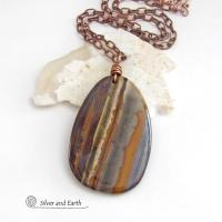 Big and bold, this one of a kind pendant necklace features a large natural tiger iron gemstone with a copper wire bail. The stone has beautiful earthy hues of various shades of brown, smoky grey, rust and creamy bands of white. It's a gorgeous stone with a nice high polish. Sure to make a striking statement, it'll make a great gift for a natural stone lover.