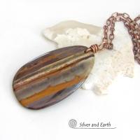 Big and bold, this one of a kind pendant necklace features a large natural tiger iron gemstone with a copper wire bail. The stone has beautiful earthy hues of various shades of brown, smoky grey, rust and creamy bands of white. It's a gorgeous stone with a nice high polish. Sure to make a striking statement, it'll make a great gift for a natural stone lover.