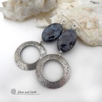 These handcrafted earrings feature natural larvikite gemstones accented with sterling silver hoop dangles with a lightly hammered texture. The stones have a pearly, grayish black hue - along with blue iridescent flashes of light which cast off a natural shimmer & shine. Perfect "go to" earrings that will look great with all wardrobe styles - dressed up or down! Larvikite originates from the Larvik region in Norway and is also called Norwegian moonstone and black labradorite. 
