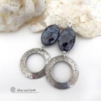 These handcrafted earrings feature natural larvikite gemstones accented with sterling silver hoop dangles with a lightly hammered texture. The stones have a pearly, grayish black hue - along with blue iridescent flashes of light which cast off a natural shimmer & shine. Perfect "go to" earrings that will look great with all wardrobe styles - dressed up or down! Larvikite originates from the Larvik region in Norway and is also called Norwegian moonstone and black labradorite.