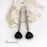 These handcrafted earrings feature long textured skinny strips of sterling silver accented with triangular-shaped black onyx stones with a matte finish. They have a contemporary modern style with a bold, edgy vibe.
