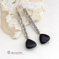 These handcrafted earrings feature long textured skinny strips of sterling silver accented with triangular-shaped black onyx stones with a matte finish. They have a contemporary modern style with a bold, edgy vibe.