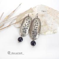 These handcrafted sterling silver earrings have a long oval shape with a hammered and hand stamped texture. Black onyx gemstones dangle from the bottom. They have a modern, earthy organic vibe that coordinates well with all wardrobe styles. Earrings are handmade in the USA by Silver and Earth Jewelry. 