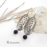 These handcrafted sterling silver earrings have a long oval shape with a hammered and hand stamped texture. Black onyx gemstones dangle from the bottom. They have a modern, earthy organic vibe that coordinates well with all wardrobe styles. Earrings are handmade in the USA by Silver and Earth Jewelry. 