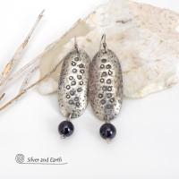 These handcrafted sterling silver earrings have a long oval shape with a hammered and hand stamped texture. Black onyx gemstones dangle from the bottom. They have a modern, earthy organic vibe that coordinates well with all wardrobe styles. Earrings are handmade in the USA by Silver and Earth Jewelry. 