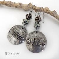 These handcrafted silver pewter earrings have a rustic, hand textured design and are accented with natural dalmatian jasper gemstones, stainless steel and vintage silver tone metal beads. They have an earthy, edgy organic style that makes a unique statement.This type of jasper is known for its spotted pattern that resembles the Dalmatian breed of dog. The matrix consists of mineral inclusions of brown iron oxide, black tourmaline & other minerals which create the natural "spots" in the stone. Handmade in th