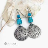 These handcrafted earrings feature silver pewter teardrop-shaped dangles with a hand stamped texture accented with natural turquoise stones and stainless steel spacer beads. They have a bold modern style with southwestern flair and will make a striking statement. They'll make a great gift for anyone that loves natural turquoise stones and southwest style jewelry. Handmade in the USA by Silver and Earth Jewelry, a New Mexico True Certified business. 