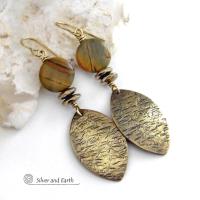 These handcrafted earrings feature textured gold brass dangles accented with natural Picasso jasper gemstones and hematite stone beads. The beads have an electroplated champagne gold tone finish which adds a touch of shimmer and shine. They have an earthy modern style that coordinates well with all wardrobe styles. Coordinating necklace is available and sold separately.