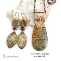 These handcrafted earrings feature textured gold brass dangles accented with natural Picasso jasper gemstones and hematite stone beads. The beads have an electroplated champagne gold tone finish which adds a touch of shimmer and shine. They have an earthy modern style that coordinates well with all wardrobe styles. Coordinating necklace is available and sold separately.