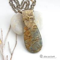 This handcrafted necklace features a natural Picasso jasper gemstone accented with a gold brass bail. The stone has a beautiful matrix with earthy hues of soft yellow, light mossy green and brown streaks. It has an earthy, modern style that coordinates beautifully with all wardrobe types. Unique and one of a kind, it makes a great gift for a natural stone lover - or a nice addition to your own jewelry collection. Comes on a 20" antiqued brass chain with lobster claw closure. 