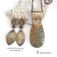 This handcrafted necklace features a natural Picasso jasper gemstone accented with a gold brass bail. The stone has a beautiful matrix with earthy hues of soft yellow, light mossy green and brown streaks. It has an earthy, modern style that coordinates beautifully with all wardrobe types. Unique and one of a kind, it makes a great gift for a natural stone lover - or a nice addition to your own jewelry collection. Comes on a 20" antiqued brass chain with lobster claw closure. 
