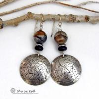 These one-of-a-kind earrings feature handcrafted sterling silver with a hammered and hand stamped texture accented with earthy natural Picasso marble gemstones, black glass and stainless steel beads. This semiprecious stone is found only in southwest Utah. It's named after the famous artist because the natural matrix of geometric lines resembles an abstract painting. The stones in this pair have a beautiful matrix pattern of distinctive swirly lines in black, grey and chocolate brown.