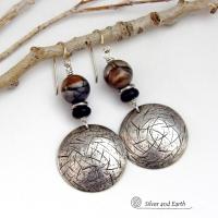 These one-of-a-kind earrings feature handcrafted sterling silver with a hammered and hand stamped texture accented with earthy natural Picasso marble gemstones, black glass and stainless steel beads. This semiprecious stone is found only in southwest Utah. It's named after the famous artist because the natural matrix of geometric lines resembles an abstract painting. The stones in this pair have a beautiful matrix pattern of distinctive swirly lines in black, grey and chocolate brown.