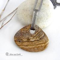 This handcrafted necklace features a large, chunky natural picture jasper stone accented with a handcrafted sterling silver bail. The stone has a beautiful natural pattern in various shades of brown, beige and gray. Big and bold, this necklace is a real one-of-a-kind statement piece - perfect for anyone that loves natural stones! It's reversible and can be worn on either side. Coordinating earrings sold separately. Handmade in the USA by Silver and Earth Jewelry.