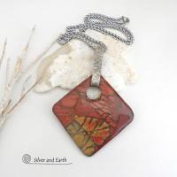This artisan handcrafted one-of-a-kind necklace features a natural red creek jasper stone accented with a hand forged sterling silver bail with a lightly hammered texture. The stone has a beautiful natural pattern in earthy hues of mossy greens, brick red, brown and orange. It's reversible and can be worn on either side. (See all photos for alternate sides). It makes a great gift for anyone that loves earthy colors and natural stones. The design is unisex so it could be worn by a man or woman.