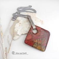 This artisan handcrafted one-of-a-kind necklace features a natural red creek jasper stone accented with a hand forged sterling silver bail with a lightly hammered texture. The stone has a beautiful natural pattern in earthy hues of mossy greens, brick red, brown and orange. It's reversible and can be worn on either side. (See all photos for alternate sides). It makes a great gift for anyone that loves earthy colors and natural stones. The design is unisex so it could be worn by a man or woman.