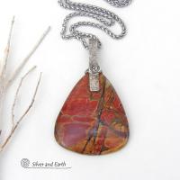 This one-of-a-kind necklace features a large stunning red creek jasper stone accented with a handcrafted sterling silver bail. The stone has a natural pattern in beautiful earthy shades of brick red, orange and green with subtle hints of golden yellow. Big and bold, this necklace is a real statement piece - perfect for anyone that loves natural stones!