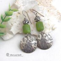 Sterling silver earrings with a hand stamped leaf design accented with natural green serpentine stones and silver pewter beads. The stones have a lime green hue and the pewter beads have a beautifully detailed 3-dimensional carved pattern of vines and leaves. They have a modern, earthy style and will make a great gift for a nature lover. The earrings are handmade and are a beautiful example of nature-inspired jewelry. 