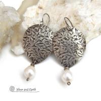 Perfect for everyday wear, these handcrafted sterling silver earrings are accented with dangling white freshwater pearls. The silver has an intricate hand stamped texture with an oxidized finish. The pearls contrast beautifully against the silver metal. They have an elegant, feminine feel with a contemporary design that looks great with all wardrobe styles. They'll make a great gift for someone born in June. Pearl is the traditional gemstone for this month. Handmade in the USA by Silver and Earth Jewelry. 