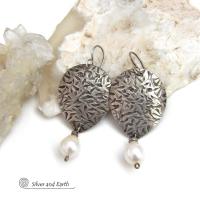 Perfect for everyday wear, these handcrafted sterling silver earrings are accented with dangling white freshwater pearls. The silver has an intricate hand stamped texture with an oxidized finish. The pearls contrast beautifully against the silver metal. They have an elegant, feminine feel with a contemporary design that looks great with all wardrobe styles. They'll make a great gift for someone born in June. Pearl is the traditional gemstone for this month. Handmade in the USA by Silver and Earth Jewelry. 