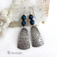 These sterling silver earrings feature handcrafted sterling silver dangles with an intricate hand stamped texture accented with deep teal blue freshwater pearls with a faceted finish.  They have a modern, elegant feel and will look great dressed up or down. They dangle from sterling silver ear wires. Handmade in the USA by Silver and Earth Jewelry. 