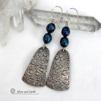 These sterling silver earrings feature handcrafted sterling silver dangles with an intricate hand stamped texture accented with deep teal blue freshwater pearls with a faceted finish.  They have a modern, elegant feel and will look great dressed up or down. They dangle from sterling silver ear wires. Handmade in the USA by Silver and Earth Jewelry. 