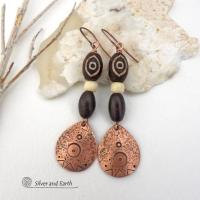 These handcrafted earrings feature copper teardrop shaped dangles with a hand stamped and hammered texture accented with Tibetan brown etched agate stones, African glass and brown wood beads. Bold and unique, they have an ethnic tribal style with boho chic flair that makes a striking statement. Perfect for women that love to wear unique and eye-catching artisan handcrafted jewelry. Handmade in the USA by Silver and Earth Jewelry. Your choice of copper or niobium hypoallergenic ear wires.