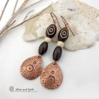 These handcrafted earrings feature copper teardrop shaped dangles with a hand stamped and hammered texture accented with Tibetan brown etched agate stones, African glass and brown wood beads. Bold and unique, they have an ethnic tribal style with boho chic flair that makes a striking statement. Perfect for women that love to wear unique and eye-catching artisan handcrafted jewelry. Handmade in the USA by Silver and Earth Jewelry. Your choice of copper or niobium hypoallergenic ear wires.