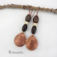 These handcrafted earrings feature copper teardrop shaped dangles with a hand stamped and hammered texture accented with Tibetan brown etched agate stones, African glass and brown wood beads. Bold and unique, they have an ethnic tribal style with boho chic flair that makes a striking statement. Perfect for women that love to wear unique and eye-catching artisan handcrafted jewelry. Handmade in the USA by Silver and Earth Jewelry. Your choice of copper or niobium hypoallergenic ear wires.