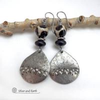 These handcrafted silver pewter earrings have a rustic, hammered texture and are accented with black and off-white Tibetan agate faceted gemstones, black glass and stainless steel beads. Bold and striking, they'll make a unique ethnic tribal statement. Perfect for women that love to wear unique, eye-catching jewelry. Handmade in the USA by Silver and Earth Jewelry.  MEASUREMENTS: Total length of approximately 2-1/2" from top of silver niobium (hypoallergenic) ear wires and 1” at widest point.