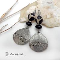 These handcrafted silver pewter earrings have a rustic, hammered texture and are accented with black and off-white Tibetan agate faceted gemstones, black glass and stainless steel beads. Bold and striking, they'll make a unique ethnic tribal statement. Perfect for women that love to wear unique, eye-catching jewelry. Handmade in the USA by Silver and Earth Jewelry.  MEASUREMENTS: Total length of approximately 2-1/2" from top of silver niobium (hypoallergenic) ear wires and 1” at widest point.