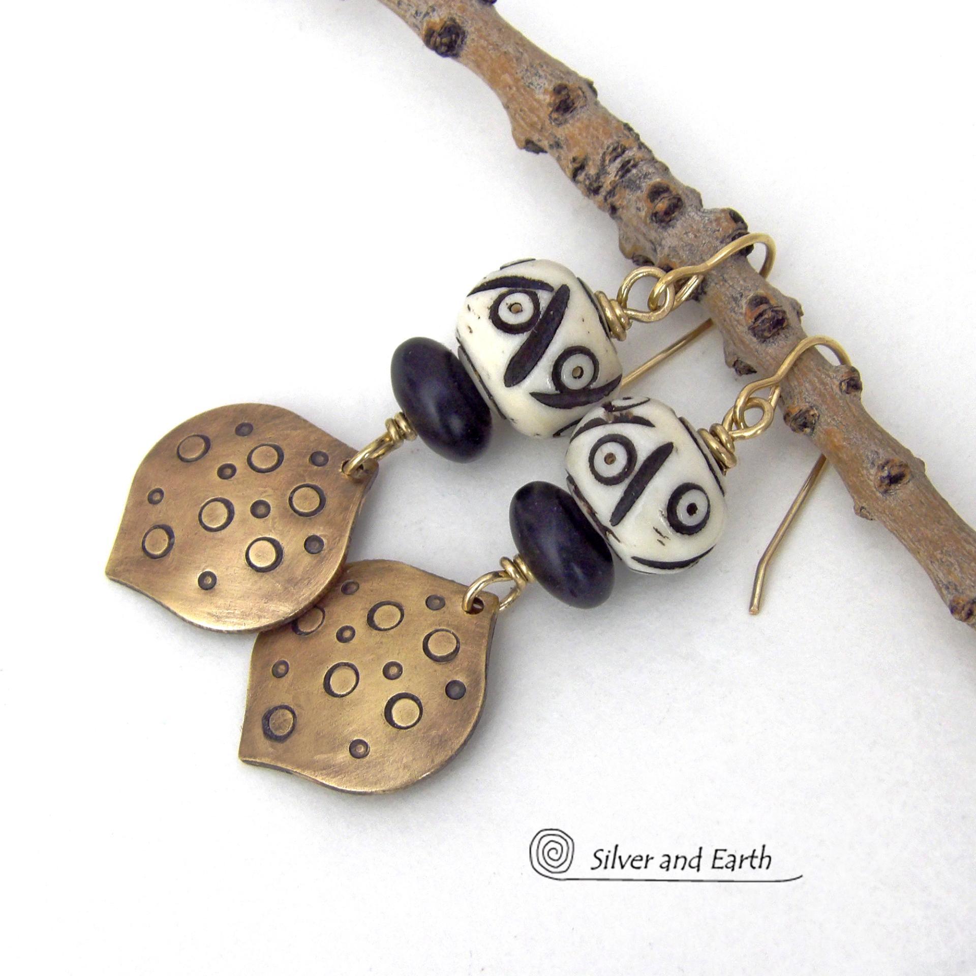 These handcrafted gold brass earrings have an ethnic, boho tribal vibe that makes a unique bold statement. They feature brass drops with a hand stamped texture accented with African carved bone beads with a bold pattern of dots and lines and matte black glass beads. Perfect for women that love unique handmade jewelry. Handmade in the USA by Silver and Earth Jewelry.
