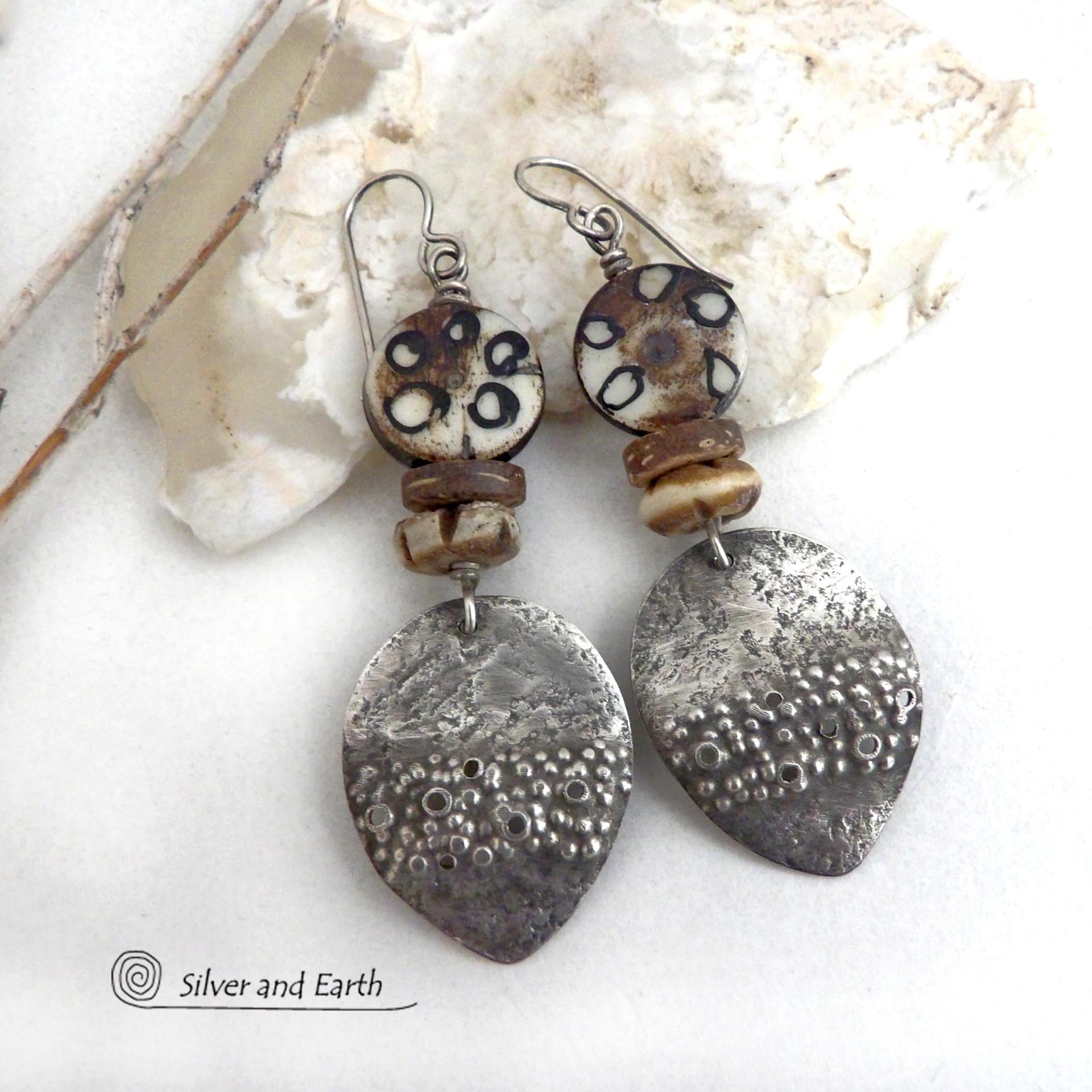 These handcrafted sterling silver earrings have a funky edgy vibe with ethnic tribal flair. They feature rustic hammered sterling silver dangles accented with African batik, bone and brown coconut shell beads. Bold and exotic, they'll add a touch a bohemian tribal style to your wardrobe that is sure to make a statement.