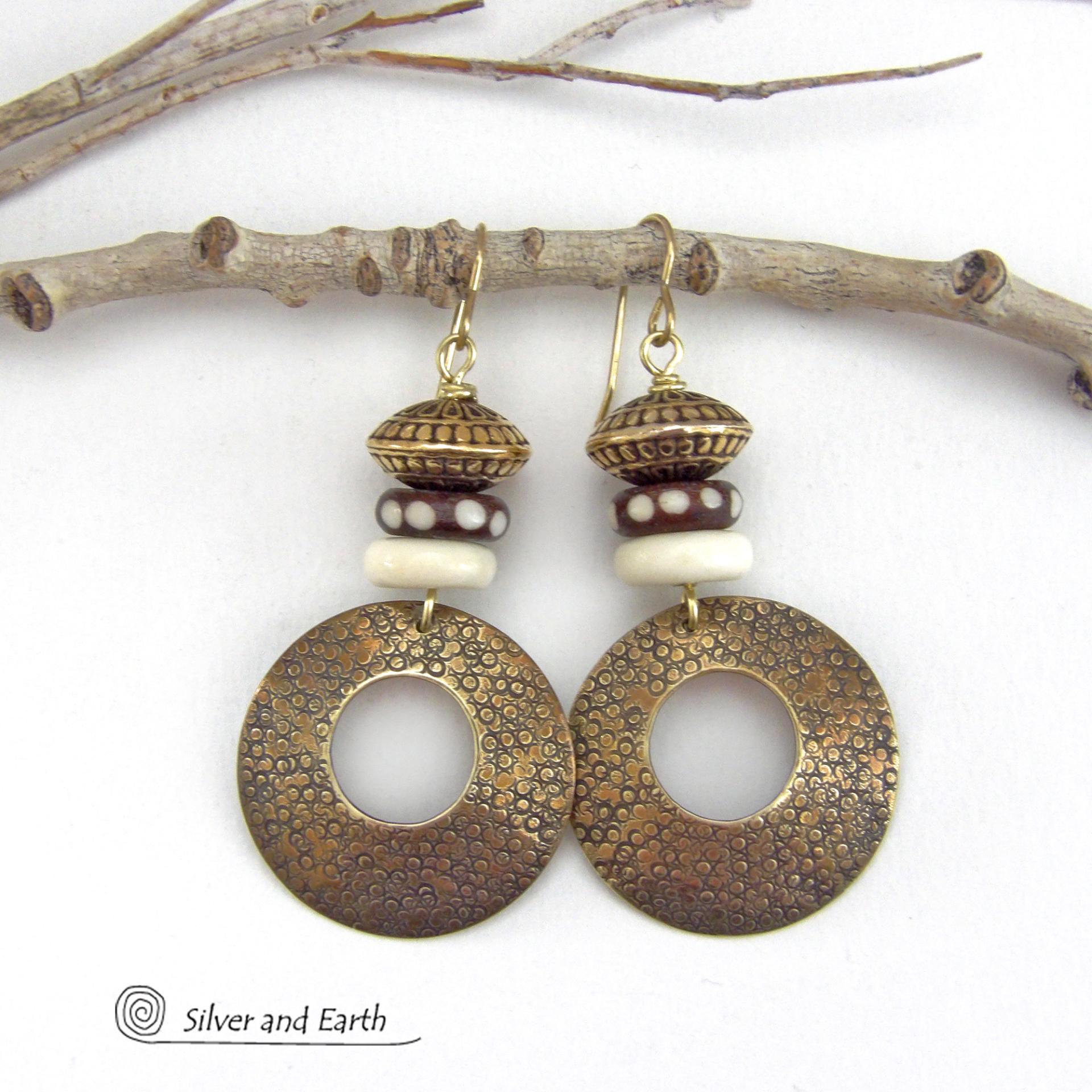 Big and bold, these handcrafted gold brass hoop earrings have a hand stamped texture and are accented with African batik bone dark brown beads with a dotted pattern, off-white bone beads and textured gold brass beads. They have an exotic ethnic and boho chic vibe that makes a striking, unique statement. Handmade in the USA by Silver and Earth Jewelry.