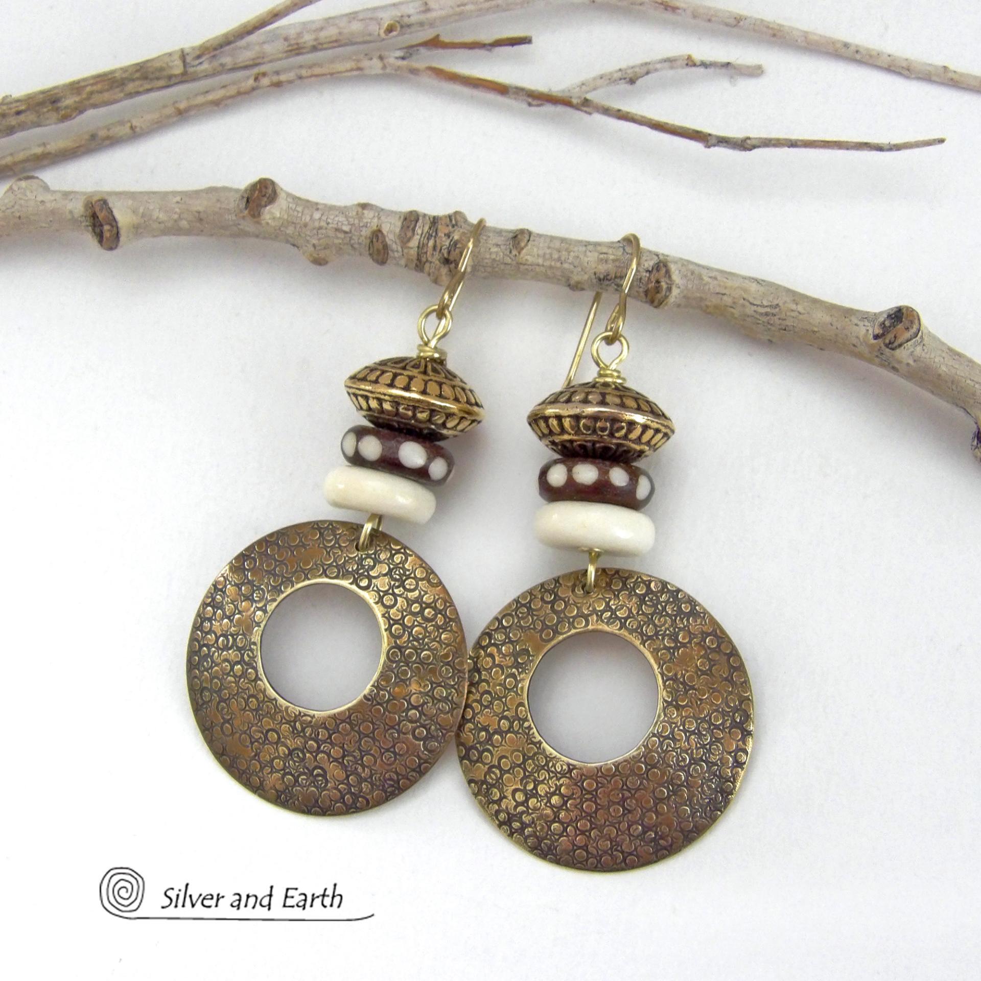 Big and bold, these handcrafted gold brass hoop earrings have a hand stamped texture and are accented with African batik bone dark brown beads with a dotted pattern, off-white bone beads and textured gold brass beads. They have an exotic ethnic and boho chic vibe that makes a striking, unique statement. Handmade in the USA by Silver and Earth Jewelry.