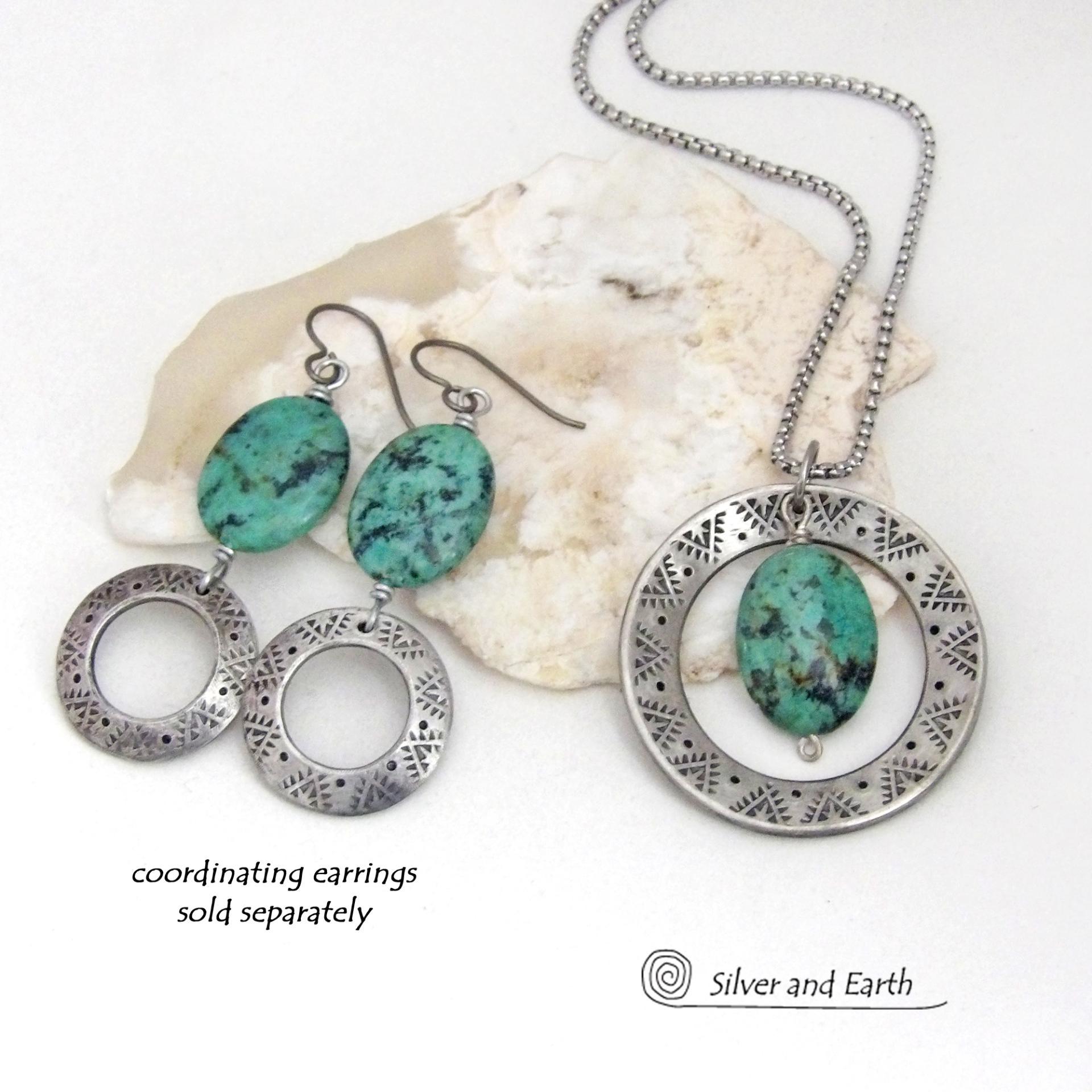 This handcrafted pendant necklace features a natural African turquoise gemstone dangling in front of a silver tone pewter circle with a hand stamped texture and oxidized finish. Unique and one of a kind, it has an earthy organic style with southwestern flair. Coordinating earrings sold separately.