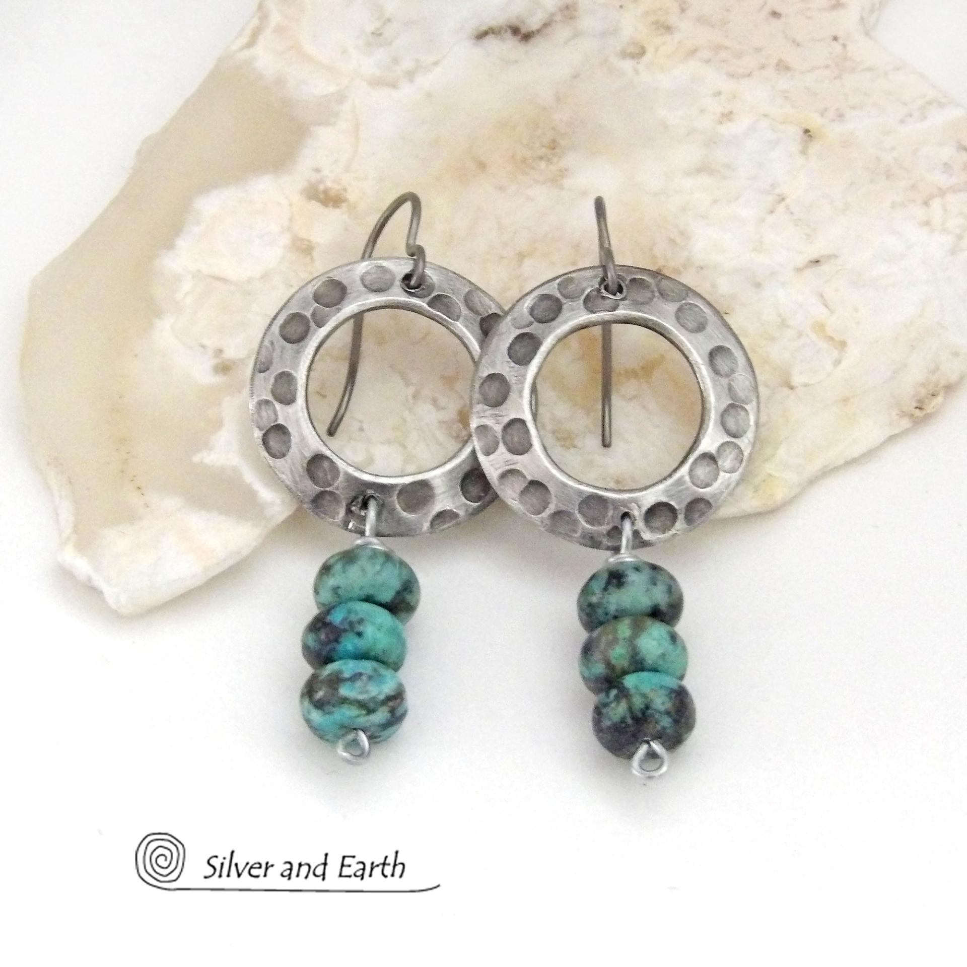 These handcrafted earrings feature oxidized silver pewter hoops with a rustic hammered and hand stamped texture accented with a stack of natural African turquoise stones. They have an earthy organic style with a modern, edgy vibe and are lightweight and comfortable to wear.