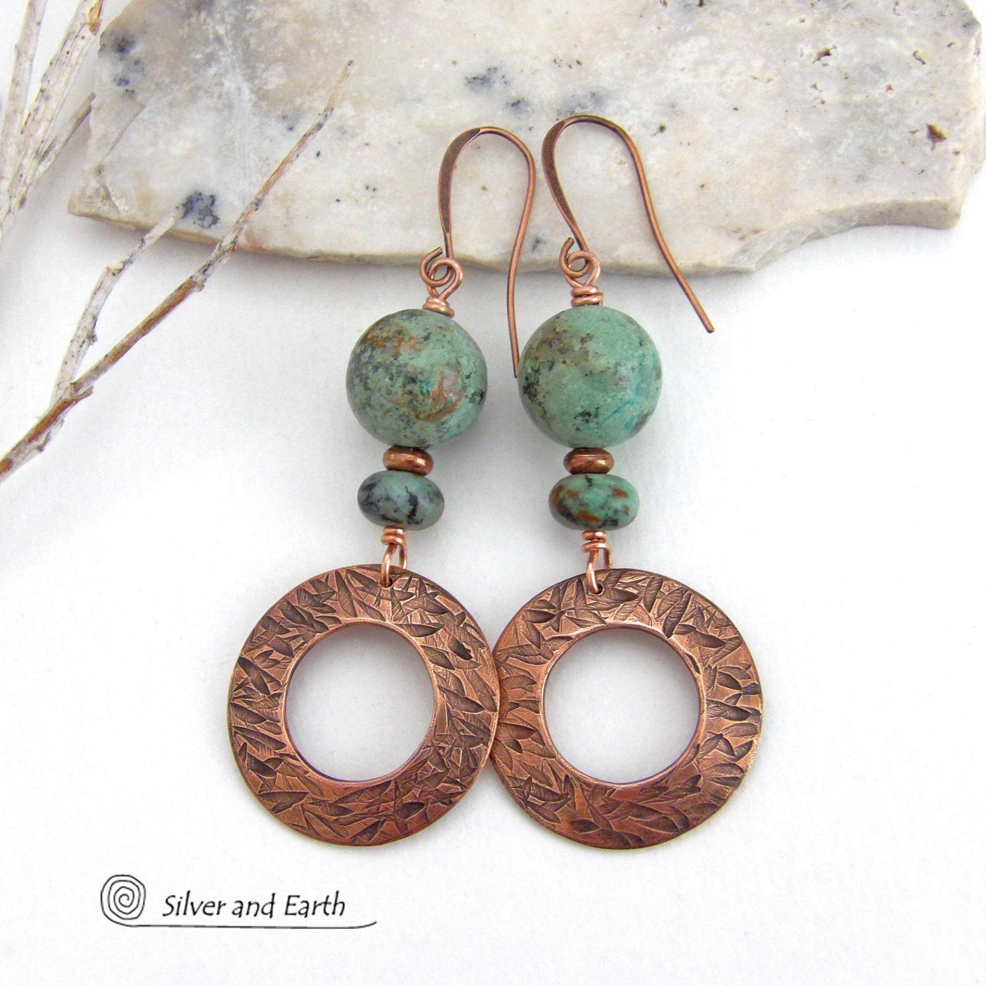  These handcrafted earrings feature round copper hoop dangles with a hand stamped texture accented with a stack of natural African turquoise stones and tiny copper beads. The stones have a pretty turquoise hue with an earthy natural black and brown matrix. These earrings have an earthy chic style with a modern bohemian flair that will coordinate beautifully with all wardrobe types. Handmade in the USA by Silver and Earth Jewelry.  Your choice of ear wires - copper or hypoallergenic niobium. 