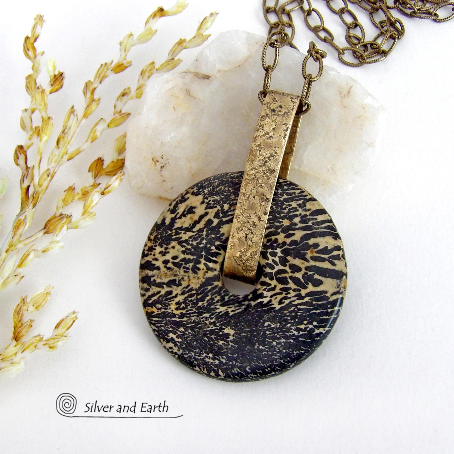 This one-of-a-kind pendant necklace features a stunning artistic jasper stone accented with a hand forged gold brass bail. This type of jasper is known for its intricate, natural patterns that resemble brushstrokes, landscapes, or abstract art. The stone in this piece has a natural bold dramatic pattern in hues of black and soft golden yellow with black streaks that resemble "feathery" dendrites. The design is modern and bold - yet classic and always in fashion. It can be worn by either a man or women. 