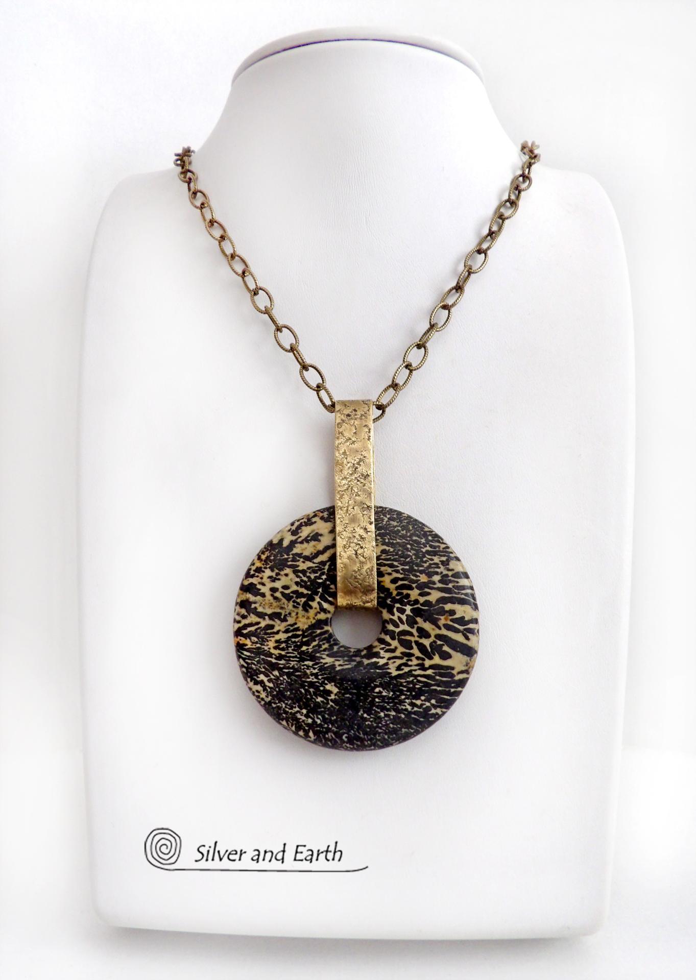 This one-of-a-kind pendant necklace features a stunning artistic jasper stone accented with a hand forged gold brass bail. This type of jasper is known for its intricate, natural patterns that resemble brushstrokes, landscapes, or abstract art. The stone in this piece has a natural bold dramatic pattern in hues of black and soft golden yellow with black streaks that resemble "feathery" dendrites. The design is modern and bold - yet classic and always in fashion. It can be worn by either a man or women. 