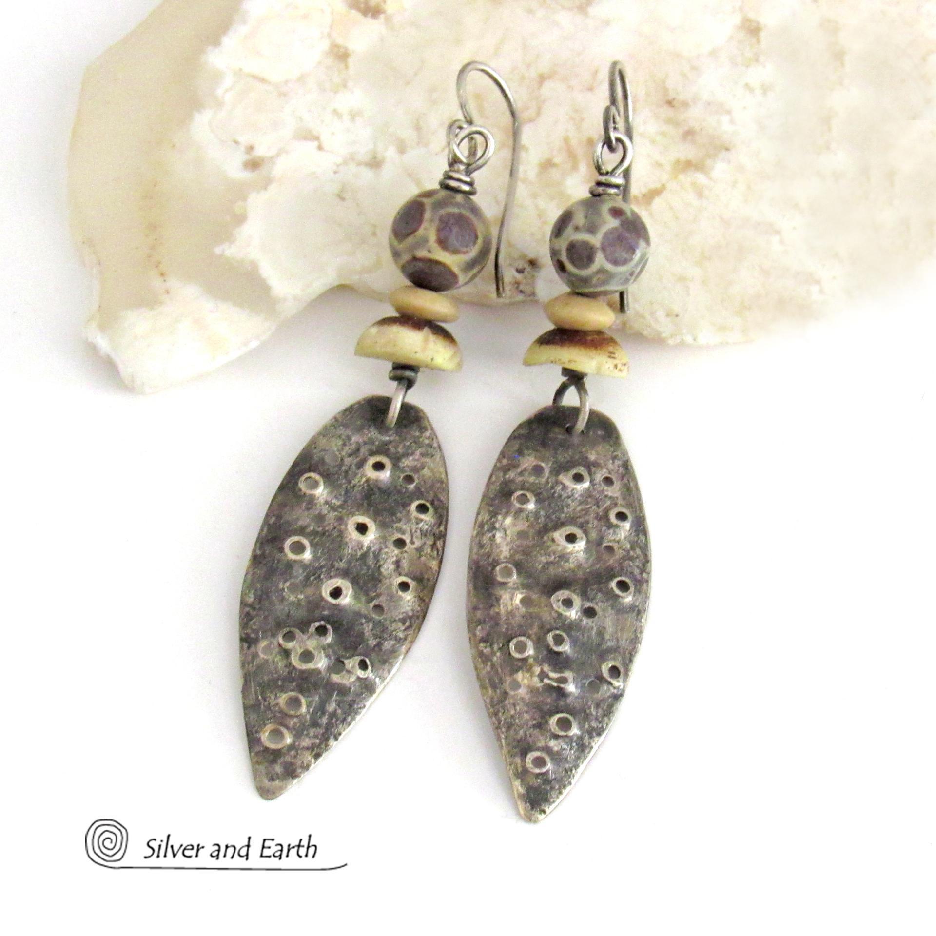 These handcrafted sterling silver earrings have a funky edgy vibe. They feature rustic hammered sterling silver dangles accented with natural asteroid jasper stones and bone beads. This type of stone is known for its unique dotted matrix in earth-tone hues of brown, gray and tan. It's also known as chocolate ocean jasper because it's found on the shores of Madagascar where ocean jasper is also found.