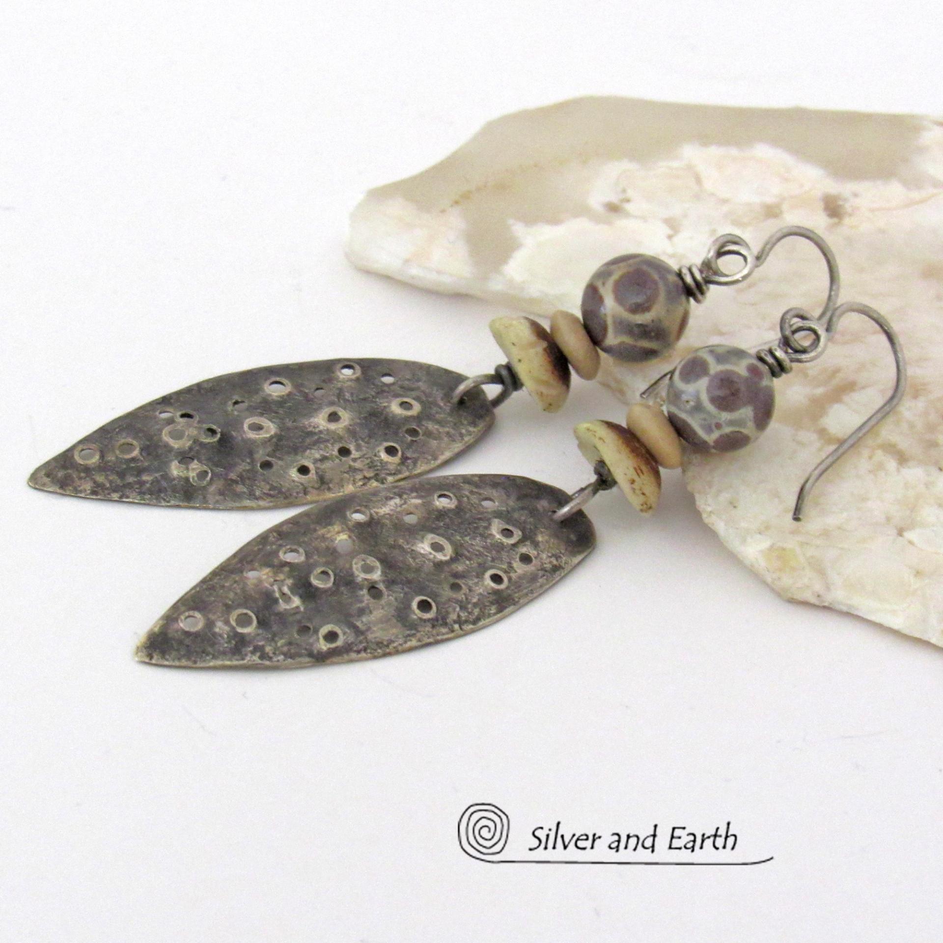 These handcrafted sterling silver earrings have a funky edgy vibe. They feature rustic hammered sterling silver dangles accented with natural asteroid jasper stones and bone beads. This type of stone is known for its unique dotted matrix in earth-tone hues of brown, gray and tan. It's also known as chocolate ocean jasper because it's found on the shores of Madagascar where ocean jasper is also found.