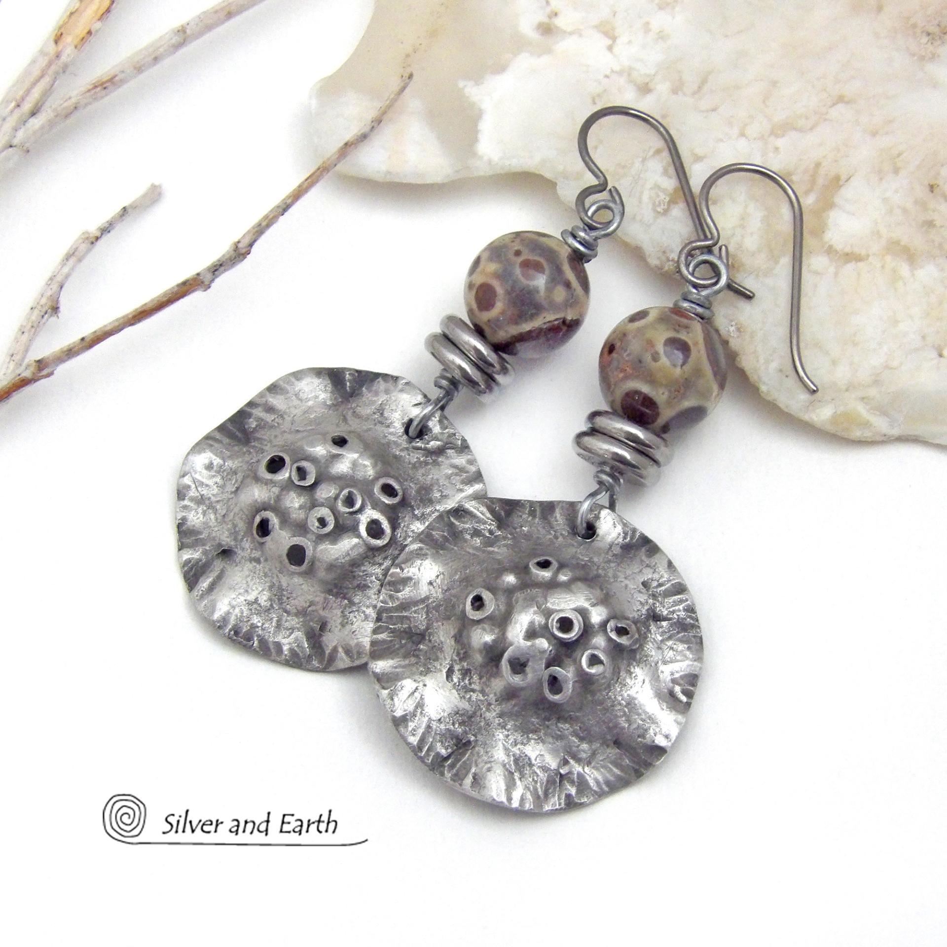 These handcrafted earrings have a bold edgy vibe. They feature rustic hammered silver tone pewter dangles accented with natural asteroid jasper stones and stainless steel beads. This type of stone is known for its unique dotted matrix in earth-tone hues of brown, gray and tan. Bold and striking - they're sure to make a statement. Perfect for women that love unique natural stones and artisan handmade jewelry. Handmade in the USA by Silver and Earth Jewelry. 