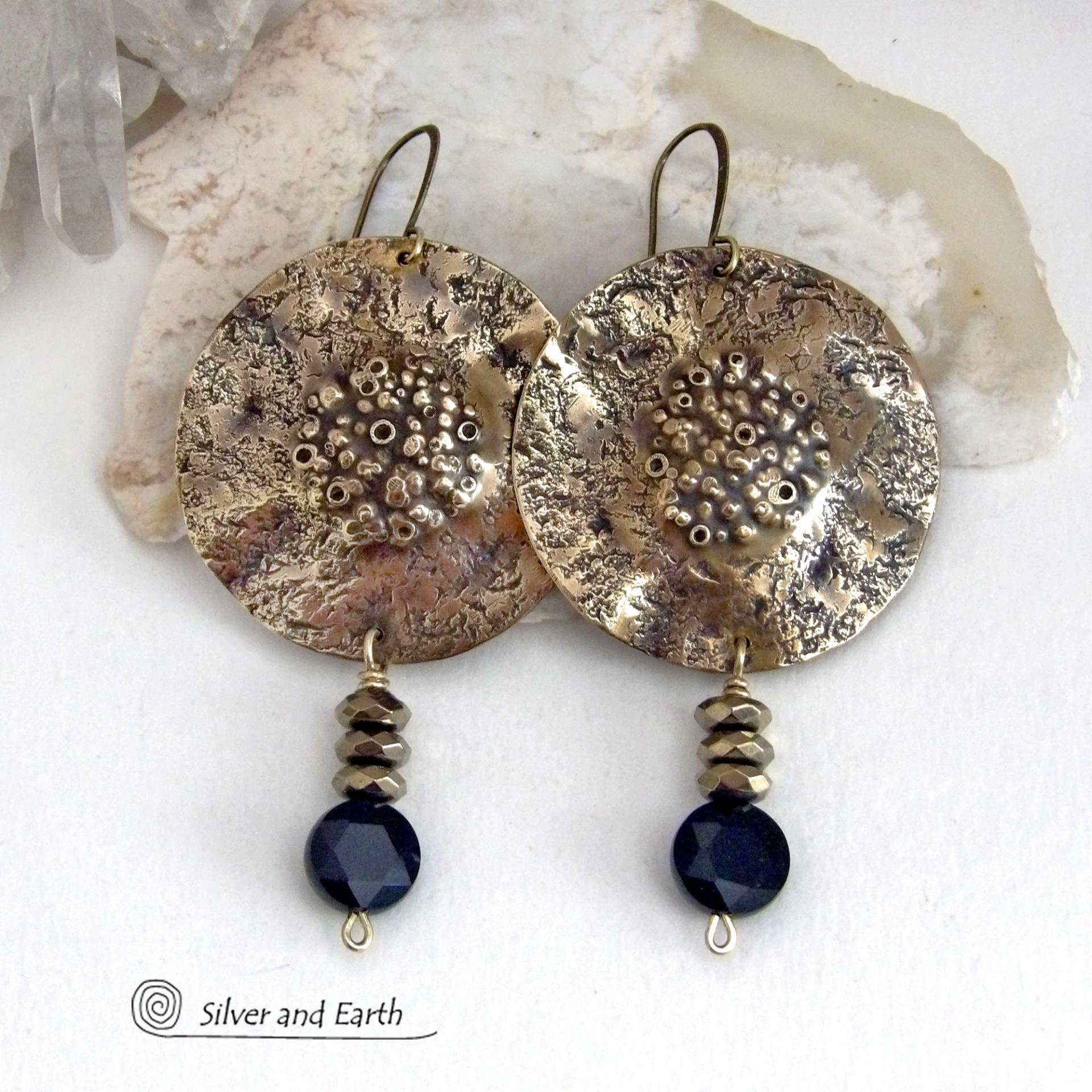 Big and bold - these handcrafted gold brass earrings have a modern chic contemporary style with an earthy, organic vibe that makes a bold, striking statement. They feature large brass circles with a rustic, organic hand textured design accented with dangling faceted black onyx gemstones and faceted hematite stones with a sparkly electroplated gold tone finish. Unique and striking, they have an earthy organic style with an exotic vibe that will look great dressed up or down. 