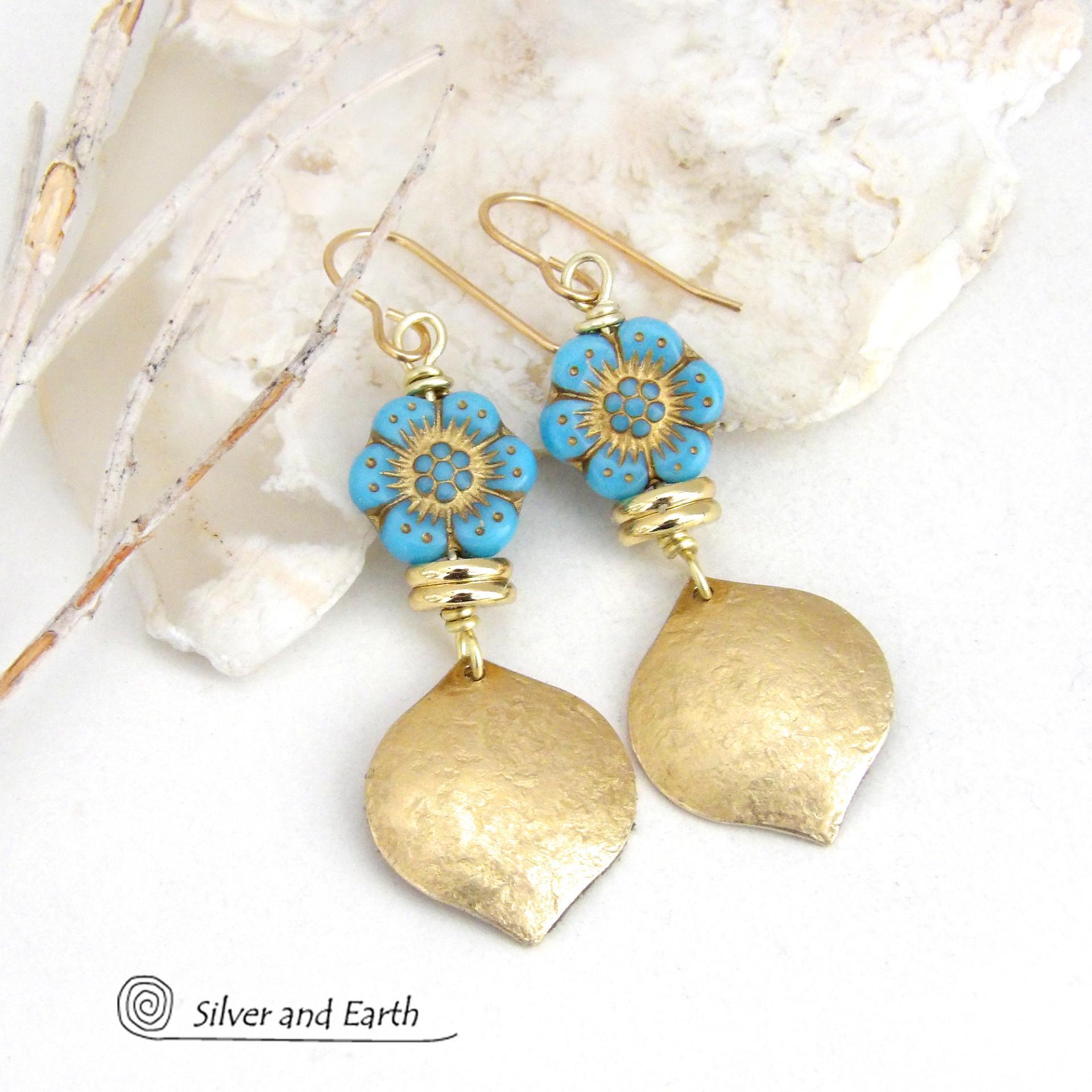 These handcrafted earrings feature gold brass dangles with a lightly hammered raw silk texture accented with glass flower beads and shiny brass beads. The flowers are a pretty shade of "bluish-turquoise" accented with gold details. These earrings have a modern elegant, earthy chic style and will make a great gift for anyone that loves flowers and nature. They'll make a great addition to your spring / summer wardrobe - or any time of year. 