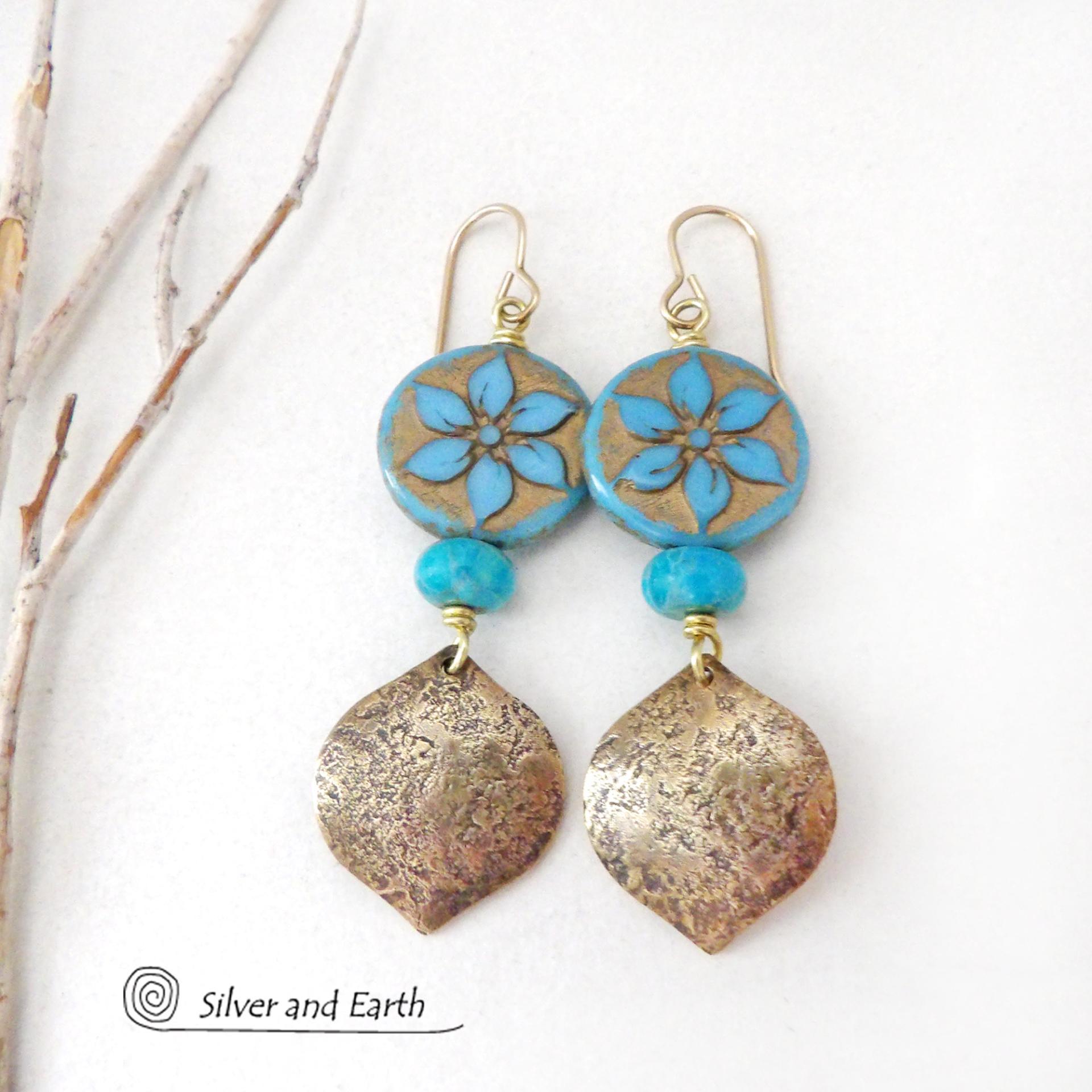 These handcrafted earrings feature gold brass dangles with a lightly hammered raw silk texture accented with glass flower beads and turquoise stone beads. The flower beads are a pretty shade of blue with golden highlights. They have an intricate carved and raised pattern on both sides of the beads. These earrings have a modern elegant, earthy chic style and will make a great gift for anyone that loves flowers and nature. They'll make a great addition to your spring / summer wardrobe - or any time of year.